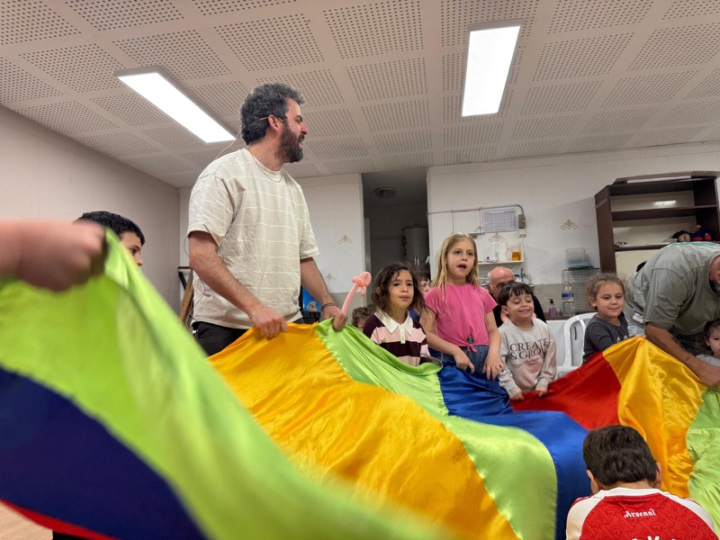 ילדים צועקים מהתרגשות במשחק מצנח צבעוני ביום הולדת